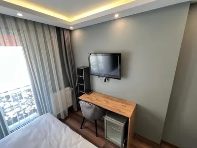 a hotel room with a desk and a tv on the wall at KMC City Hotel in Lüleburgaz