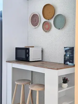 a counter with a microwave and three plates and stools at Excellent Apartments Fatih Citadel in Istanbul