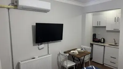 a small kitchen with a table and a tv on the wall at balatlifesuites in Istanbul