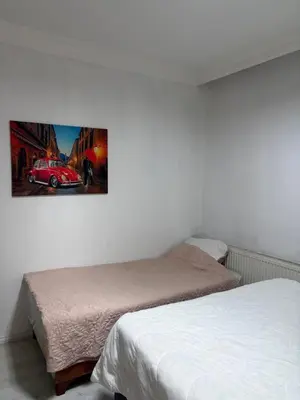 a bedroom with two beds and a picture of a car on the wall at Üsküdar Sahil Konaklama in Istanbul