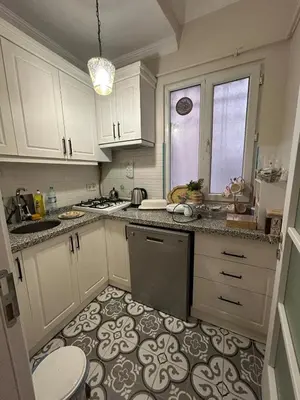 a kitchen with white cabinets and a tile floor at Bohemian Antique House in Colorful Balat in Istanbul