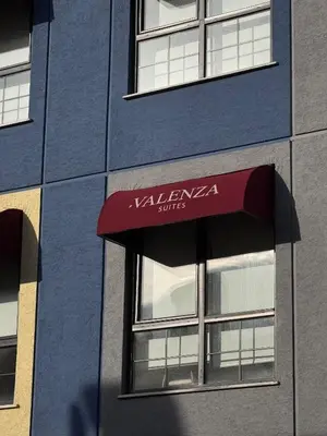 a blue building with a red awning on it at Valenzasuites in Tuzla