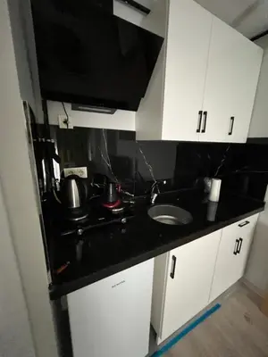 a kitchen with white cabinets and a black counter top at House in Istanbul