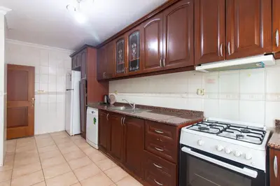 a kitchen with wooden cabinets and a stove top oven at Spacious & Modern 3BR Apartment Central Şişli in Istanbul