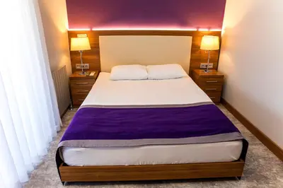 a bedroom with a large bed with a purple blanket at Business Palas Otel in Kocaeli