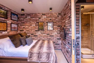 a brick walled bedroom with a bed and a bench at Palivor Çiftliği in Korfo