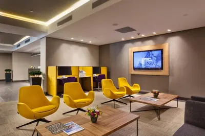 a waiting room with yellow chairs and tables at Fraser Place Antasya Istanbul in Istanbul