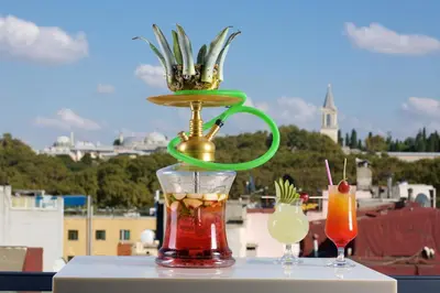 a vase with a drink on a table with two cocktails at Glamour Hotel Istanbul Sirkeci in Istanbul