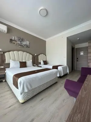a large bedroom with two beds and purple chairs at Ceti̇n Presti̇ge Resort in Erdek