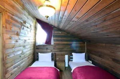 two beds in a room with wooden walls at Uludag Orman Koskleri in Uludag