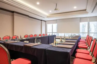 a conference room with long tables and red chairs at Clarion Hotel Istanbul Mahmutbey in Istanbul