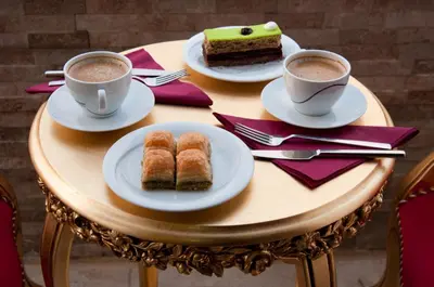 a table with two cups of coffee and two plates of cake at Vali Konak Hotel Nişantaşı in Istanbul