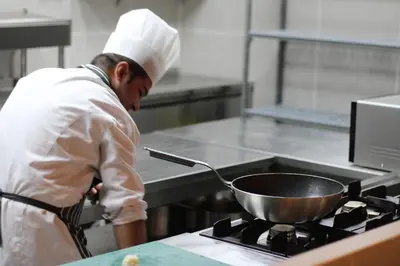 a chef standing in a kitchen stirring a pot on a stove at Ramada Plaza By Wyndham Sultanahmet in Istanbul