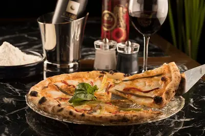 a pizza on a plate on a table with a glass of wine at Nabu Hotel Karaköy in Istanbul