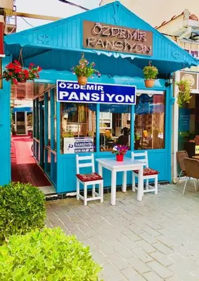 a blue building with a table and chairs in front of it at Ozdemir Pansiyon in Heybeliada