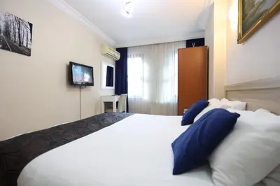 a bedroom with a large white bed with blue pillows at Arven Hotel in Istanbul