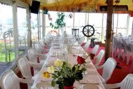 a long table with white chairs and flowers on it at Gizlibahce Hotel in Karaburun