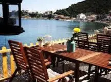 a wooden table with chairs and a view of the water at Gizlibahce Hotel in Karaburun
