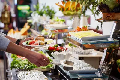 a person is preparing food at a buffet at Güneş Hotel Merter in Istanbul