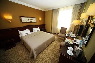 a hotel room with a bed and a chair and a television at Bilek Istanbul Hotel in Istanbul