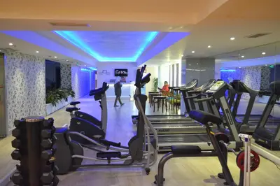a gym with cardio equipment and people in the background at Bilek Istanbul Hotel in Istanbul