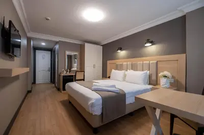 a bedroom with a large bed with a desk and a table at Berr Hotel in Istanbul