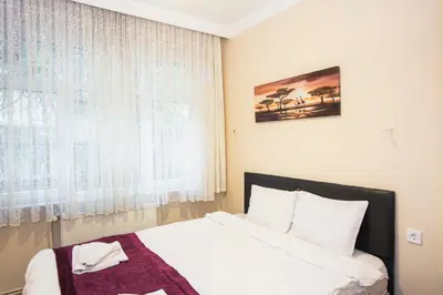 a bedroom with a bed with white sheets and a window at Berce Apartments in Istanbul