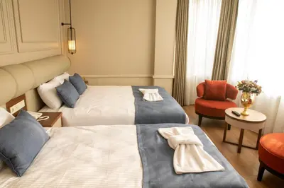 a hotel room with two beds and a red chair at Martinenz Hotel in Istanbul