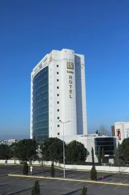 a tall white building with a parking lot in front of it at Baia Bursa Hotel in Bursa