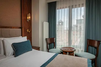 a bedroom with a bed and two chairs and a window at Triton Hotel in Istanbul
