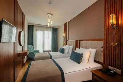 a hotel room with two beds and a chair at Triton Hotel in Istanbul