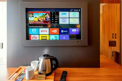 a television on a wall above a table with a coffee pot at Harmony Hotel Istanbul & SPA in Istanbul