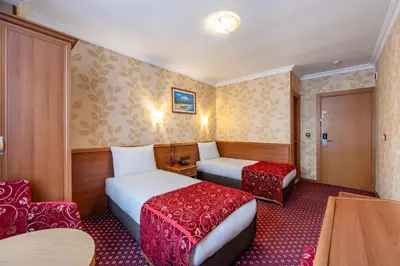 a hotel room with two beds and a chair at Hotel Bristol in Istanbul