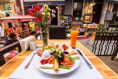 a plate of food on a table with a vase of flowers at Kuzen Otel in Istanbul