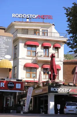 a white building with red umbrellas in front of it at Rodosto Hotel in Tekirdag