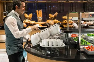 a man standing in a kitchen preparing food at Lionel Hotel Istanbul in Istanbul