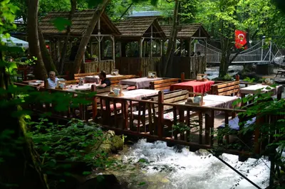 a restaurant with tables on a bridge over a river at Karaaslan Kamping Tesisleri in Kazandere