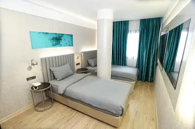 two beds in a hotel room with green curtains at Milord Hotel in Istanbul