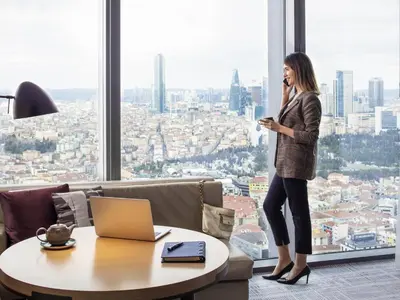 a woman standing in front of a window talking on a cell phone at Fairmont Quasar Istanbul Hotel in Istanbul