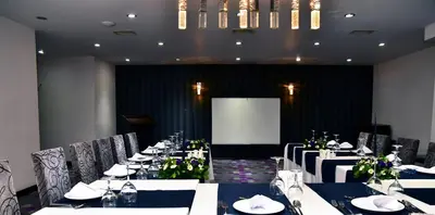 a dining room with white tables and chairs and a screen at Hande Hotel in Mustafakemalpaşa