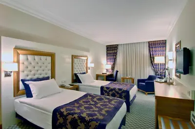 a hotel room with two beds and a chair at Tugcu Hotel Select in Bursa