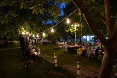 a group of people sitting at tables in a park at night at Heybeli Hotel in Mudanya