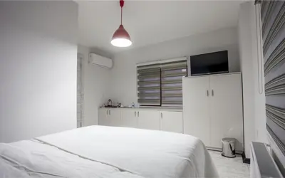 a white bedroom with a bed and a flat screen tv at Taksim Sem House in Istanbul