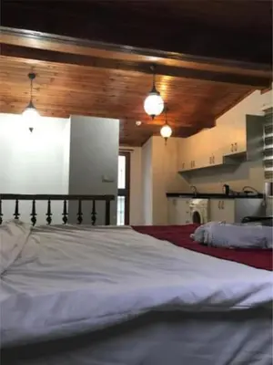 a bedroom with a white bed and a kitchen at Taksim Sem House in Istanbul