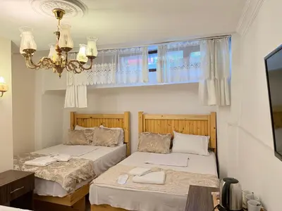 two beds in a room with a window and a chandelier at Magnificent Hotel in Istanbul