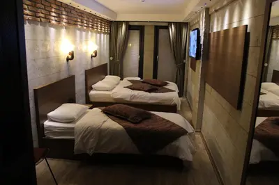 a room with three beds and a tv on the wall at Elibol Hotel Old City in Istanbul