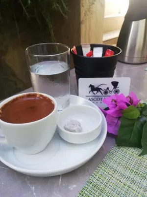 a plate with a cup of coffee and a glass of water at Ascot Hotel Büyükada in Buyukada