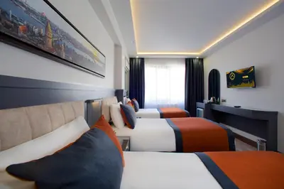 a hotel room with three beds with orange and white at Hotel Eyfel in Istanbul