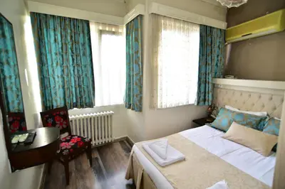 a bedroom with a bed and a desk and windows at Hotel Han in Istanbul