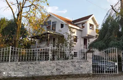 a white house behind a fence at Butik Hotel Maşukiye in Masukiye